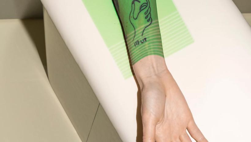 A close-up of a person's forearm resting on the bed in the Neko Scan Room, with a green light illuminating the arm.